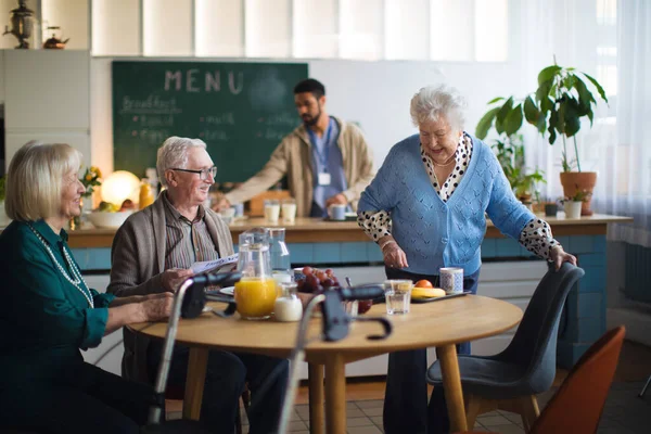 Grupo de alegres personas mayores que disfrutan del desayuno en el centro de atención a hogares de ancianos. — Foto de Stock