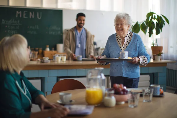 Усміхнені літні жінки насолоджуються сніданком у центрі догляду за домогосподарками . — стокове фото