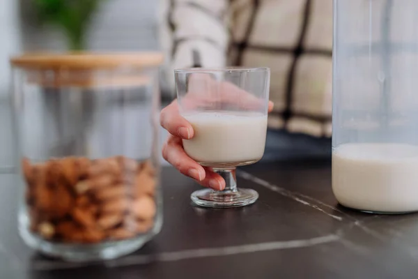 Donna irriconoscibile che tiene il bicchiere con latte di mandorla in cucina. Concetto di prodotto vegano sano. — Foto Stock