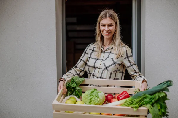 Žena hospodářství dodané bedny se zeleninou a ovocem od místního zemědělce, udržitelný životní styl koncept. — Stock fotografie