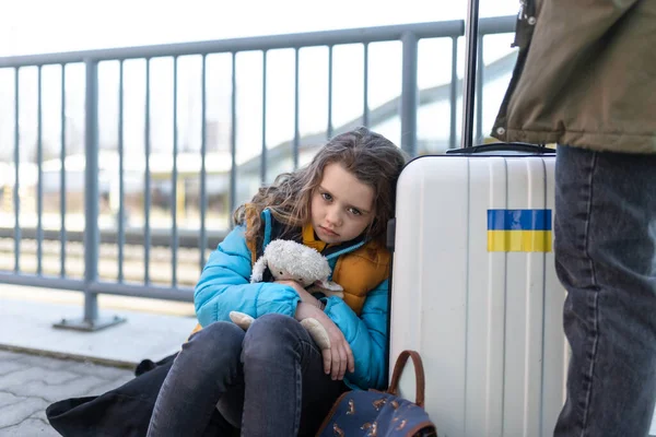 Triste niño inmigrante ucraniano con equipaje esperando en la estación de tren, concepto de guerra ucraniana. — Foto de Stock