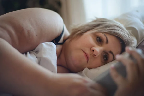 Depressed lonely fat woman lying in bed at home and thinking. — Stock Photo, Image