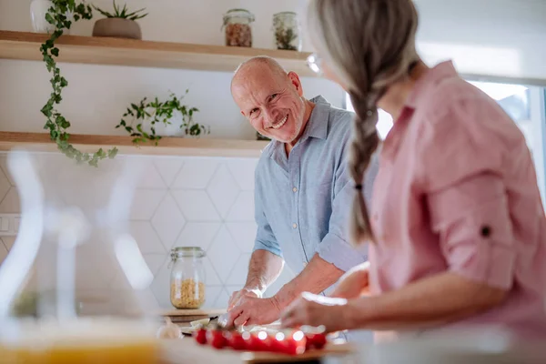 Счастливая пожилая пара готовит вместе дома. — стоковое фото
