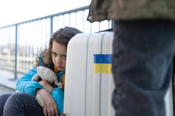 Smutný ukrajinský imigrant dítě s zavazadly čeká na vlakovém nádraží, ukrajinský válečný koncept. — Stock fotografie