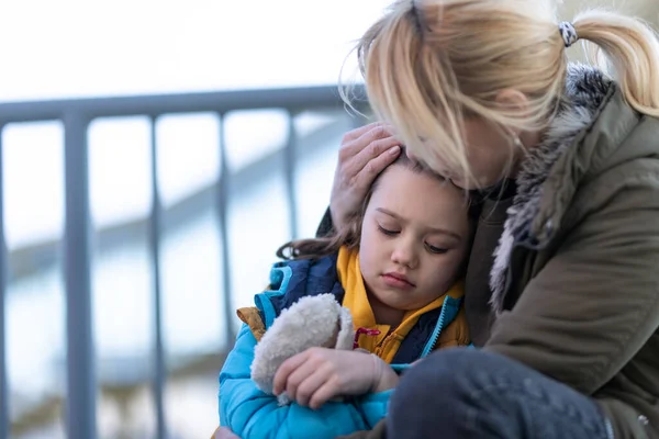 Madre ucraina immigrati con figlia con bagagli in attesa alla stazione ferroviaria, concetto di guerra ucraino. — Foto Stock