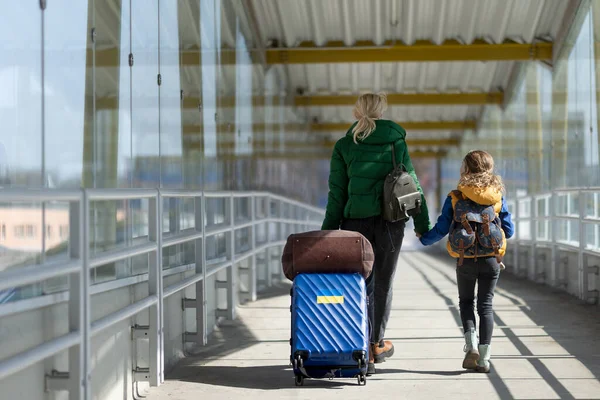 Hátsó nézet az ukrán bevándorló anya gyermekkel poggyász séta a vasútállomáson, ukrán háborús koncepció. — Stock Fotó