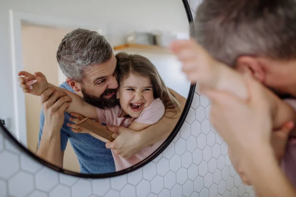 Ayah menyikat rambut putri kecilnya di kamar mandi, konsep rutinitas pagi. — Stok Foto