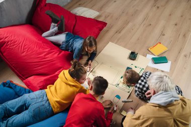 High angle view of group of kids with their teacher working on IT project together at classroom.