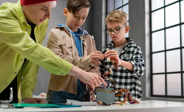 Діти з учителем працюють разом над проектом з електричними іграшками та роботами в класі робототехніки — стокове фото