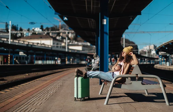 Mujer viajera joven sentada sola en la plataforma de la estación de tren con equipaje. — Foto de Stock