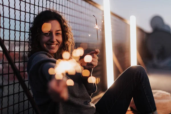 Jovem mulher com sparklers se divertindo no telhado da cidade, close-up. — Fotografia de Stock