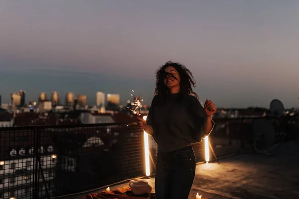 Jovem mulher com faíscas se divertindo e dançando no telhado da cidade, de perto. — Fotografia de Stock