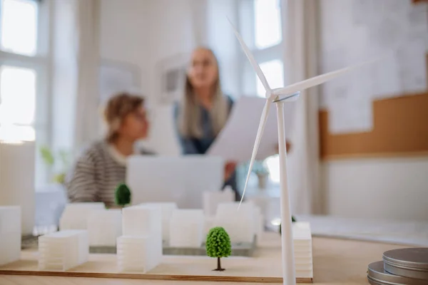 Women eco architects working together in office, with wind turbine in foreground. — стоковое фото
