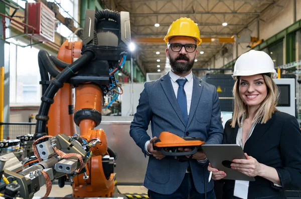 Ingeniero jefe y director de proyecto en la moderna fábrica industrial con brazos robot hablando y optimización de la planificación de la producción. — Foto de Stock