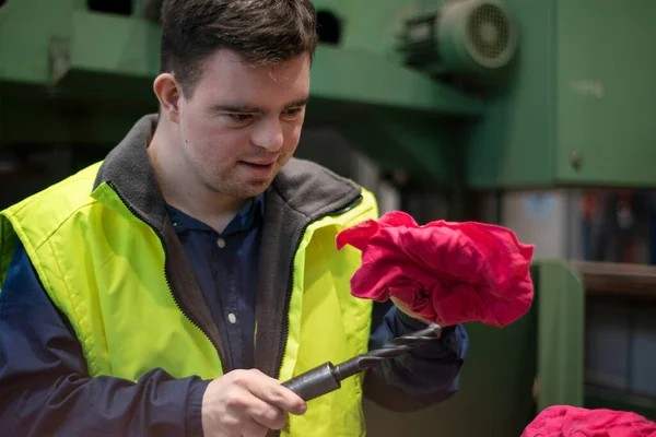 Junger Mann mit Down-Syndrom arbeitet in Industriefabrik, Konzept der sozialen Integration. — Stockfoto