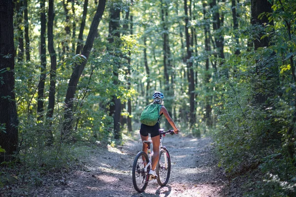 Rear view of active senior woman biker cycling outdoors in forest. — Foto de Stock