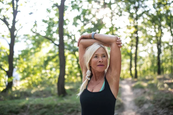 Portrait of active senior woman runner stretching outdoors in forest. — Foto Stock