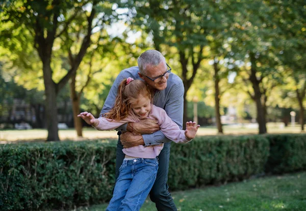 Glad farfar kramar sitt lilla barnbarn utomhus i parken. — Stockfoto