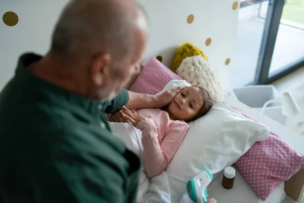 Büyükbaba hasta torununa bakıyor. Yatakta yatıyor.. — Stok fotoğraf