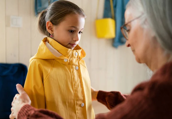 Grootmoeder helpt kleindochter om zich klaar te maken om van huis naar school te gaan. — Stockfoto