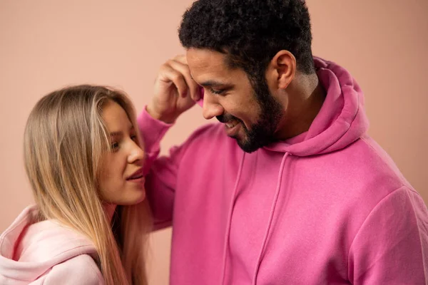 Retrato de estudio de moda de una feliz pareja joven con capucha posando sobre fondo rosa. — Foto de Stock