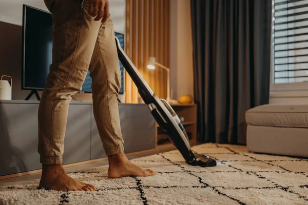 Lowsection of man hoovering carpet with vacuum cleaner in living room — Stock fotografie