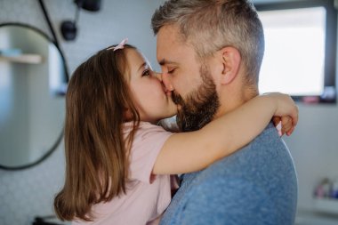 Father kissing his little daughter in bathroom.