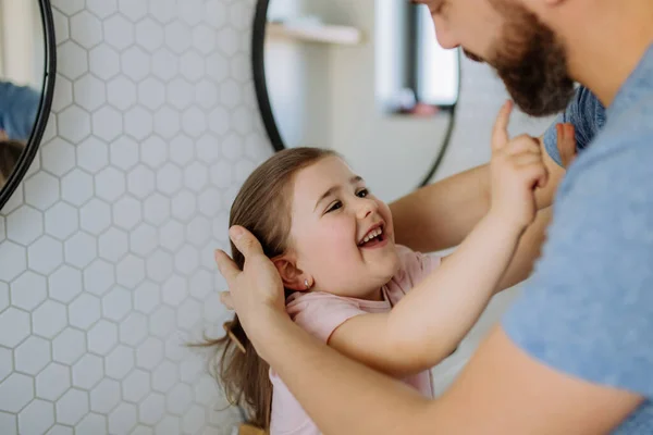 Vader controleert zijn dochters tanden in de badkamer, ochtend routine concept. — Stockfoto