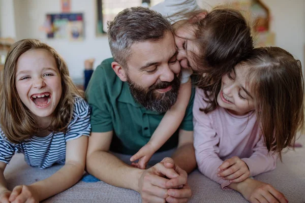 Padre allegro con tre piccole figlie che giocano insieme a casa. — Foto Stock