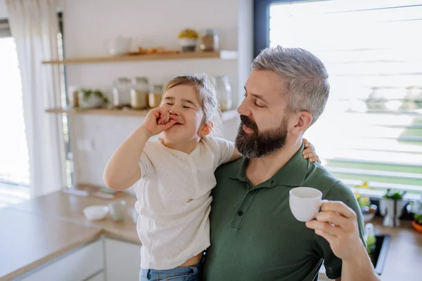 Father holding his little daughter when drinking coffee at home. — Stock Photo, Image