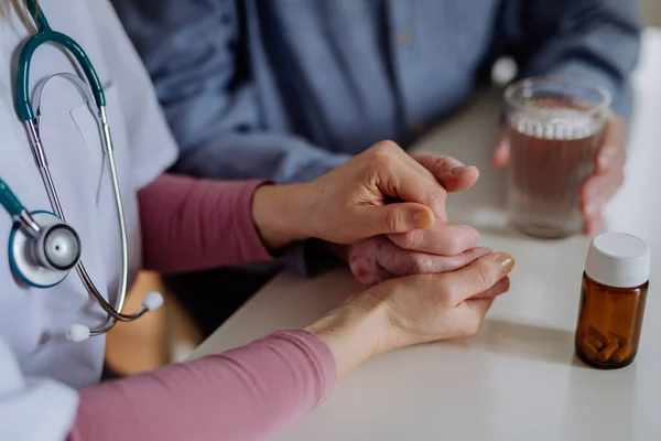 Primer plano del médico cogido de la mano del paciente mayor y consolándolo durante la visita médica en casa. —  Fotos de Stock