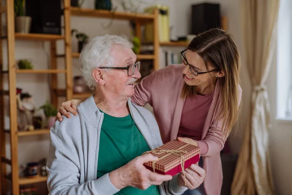 Femme heureuse surprenant son père aîné en lui rendant visite à la maison et apporter cadeau. — Photo