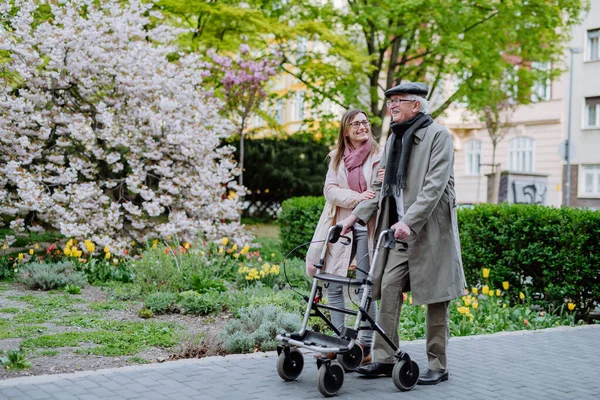 Старший чоловік з пішохідною рамкою і доросла дочка на відкритому повітрі на прогулянці в парку . — стокове фото