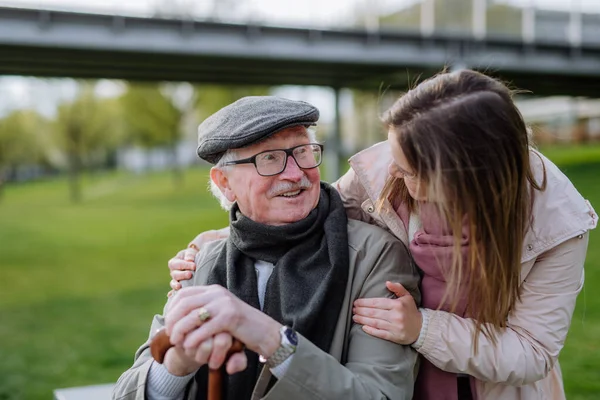 Happy senior with his adult daughter sitting outdoors in park. — Stock fotografie