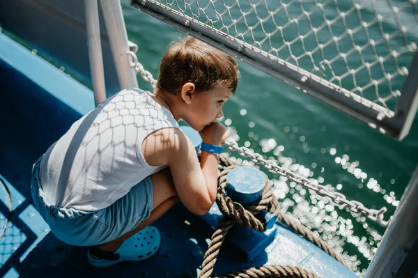 Pequeño niño curioso mirando el agua de la lancha. — Foto de Stock