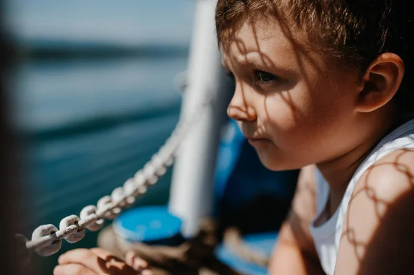 Malý zvědavý chlapec dívá na vodu z motorového člunu. — Stock fotografie
