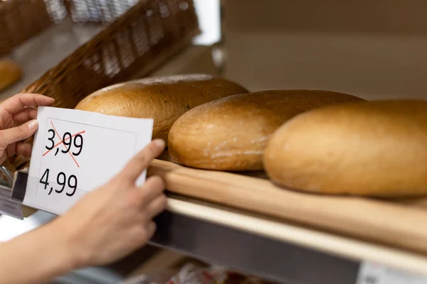 Γυναικείο κατάστημα βοηθός αλλαγή των τιμών του ψωμιού στο σούπερ μάρκετ, η έννοια της αύξησης του πληθωρισμού — Φωτογραφία Αρχείου