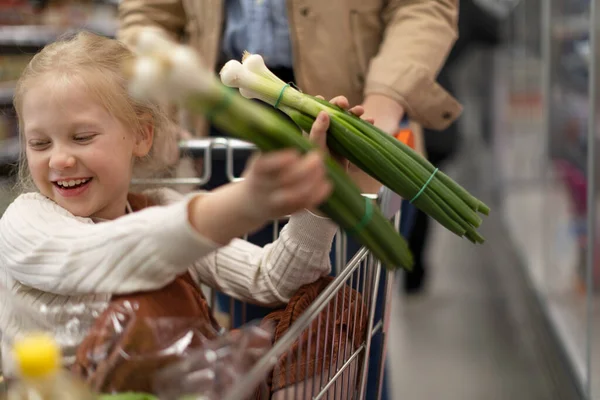 Little girl sitting in the trolley during family shopping in hypermarket — Zdjęcie stockowe