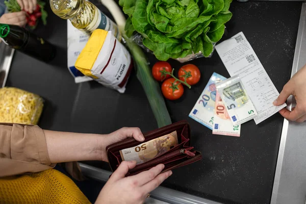 Close-up of woman giving money at the cash desk in supermarket