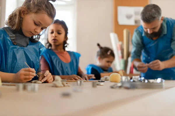 Groupe de petits enfants avec professeur travaillant avec de l'argile de poterie pendant les cours d'art créatif et d'artisanat à l'école. — Photo