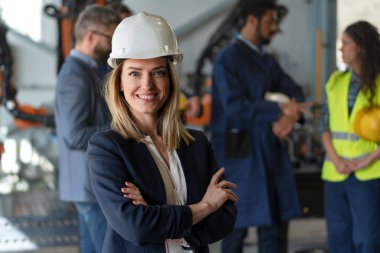 Portrait of female chief engineer in modern industrial factory looking at camera.