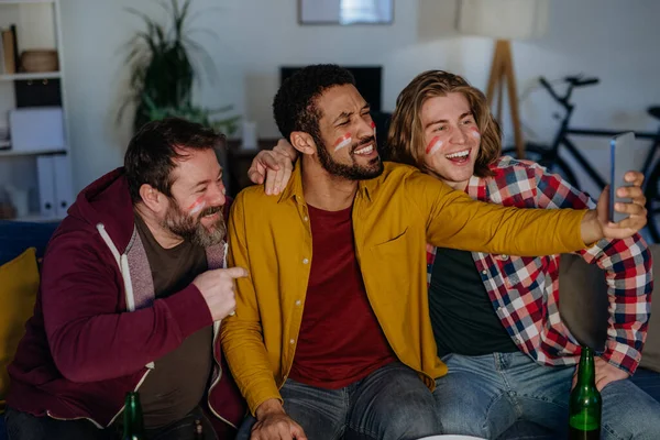 Felices amigos aficionados al fútbol viendo fútbol en casa y tomando selfie — Foto de Stock