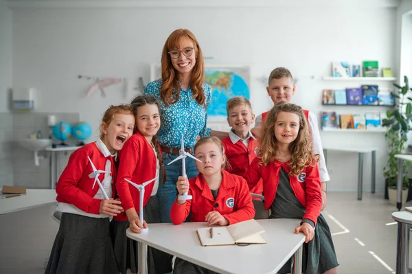 A group of school children with teacher holding wind turbines and learning about eco-friendly renewable sources of energy — Fotografia de Stock