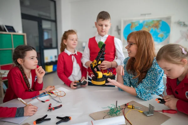 Група дітей з молодим вчителем науки програмування електричних іграшок та роботів у класі робототехніки — стокове фото