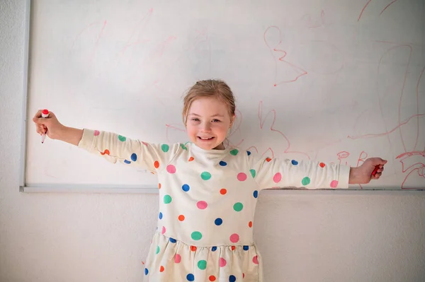 Happy little schoolgirl with down syndrome standing in front of whiteboard and looking at camera — Foto Stock