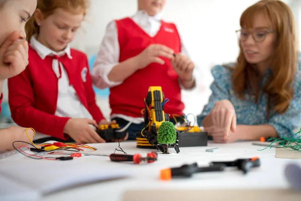Група дітей з молодим вчителем науки програмування електричних іграшок та роботів у класі робототехніки — стокове фото