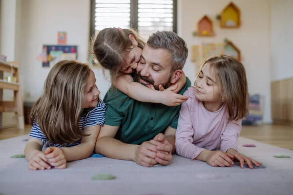 Веселий батько з трьома маленькими доньками, які грають разом вдома . — стокове фото