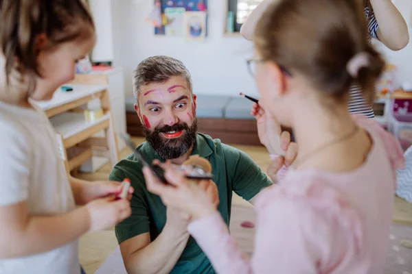 Tiga gadis kecil memakai make up pada ayah mereka, hari ayah dengan anak perempuan di rumah. — Stok Foto