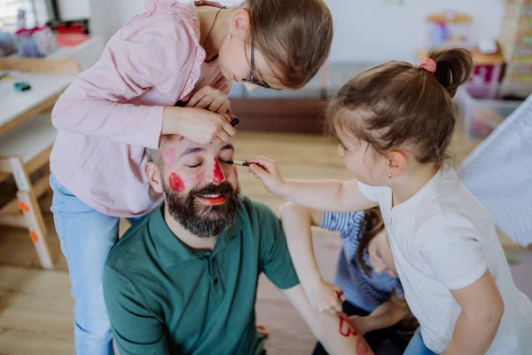 Three little girls putting on make up on their father, fathers day with daughters at home. — Stock Photo, Image