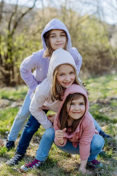 Three little sisters looking at camera in spring nature together. — ストック写真